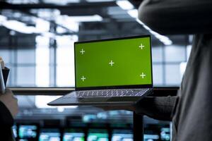 Engineers in data center using green screen laptop, implementing predictive analytics scripts, reviewing equipment health, adjusting system parameters, coordinating maintenance tasks photo