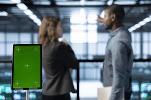 Close up of chroma key tablet and teamworking programmers in data center adjusting power management settings. Isolated screen mockup device in front of technicians in blurry background photo