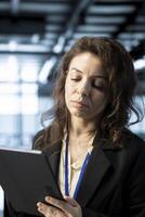 Programmer in data center using tablet, verifying compliance requirements of supercomputers. Woman in server hub optimizing resource utilization, maintaining stable infrastructure using device photo