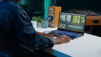 editor selecting key frames to use while doing montage, working from home on notebook device. Woman using mouse to edit movie project footage in apartment office, camera A photo