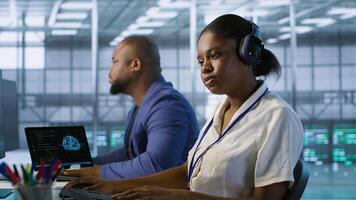 Data center engineer wearing headphones enjoying songs, maintaining company network infrastructure. Woman in server hub listening music while ensuring optimal system performance, camera A photo