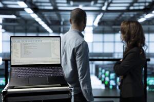 Focus on lines of code on laptop display used by teamworking data center colleagues to run security patches. Close up of programming language on notebook used by server room IT experts scanning gear photo