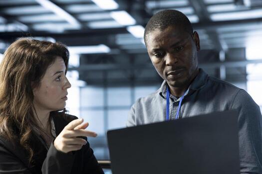 Teamworking coworkers in data center workspace using automation tools on tablet. IT staff members ensuring continuous uptime of server farm, managing data flows with device photo