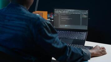 Software developer writes code on laptop screen while in apartment office using Java programming languages. Programmer remotely working on fixing database errors while working from home, camera A photo