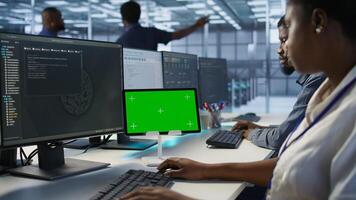 IT experts using green screen tablet, working together in server farm to optimize it for data processing requirements. Close up of coworkers coding on chroma key device in data center, camera A photo