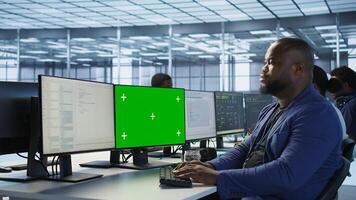Data center computer scientist using mockup monitor, configuring and troubleshooting hardware. Server hub IT specialist ensuring optimal system performance with green screen PC photo