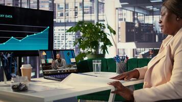 Black director pitching a new project to shareholders group on teleconference call, discussing about funding for global development. Female CEO leader with ambition for business growth. Camera B. photo