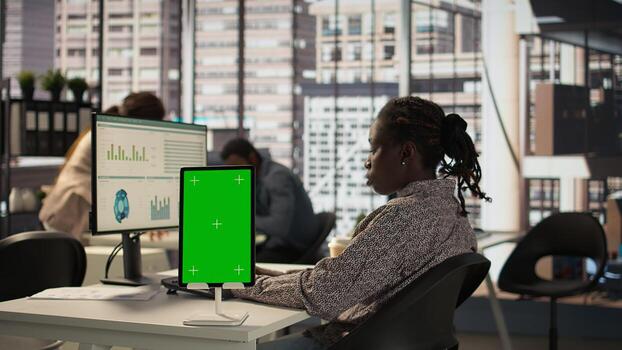 hembra gerente sentado a puesto de trabajo con verde pantalla en dispositivos, trabajando en resolviendo administrativo Tareas para empresa crecimiento. desarrollando actuación métrica a apoyo firma objetivos. cámara b. foto