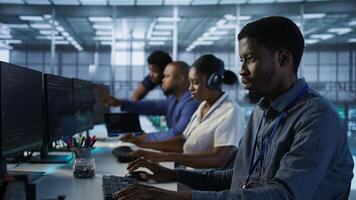 Software developers in data center implementing AI predictive maintenance systems. Focus on man in server hub office using artificial intelligence to identify hardware failures, camera A photo