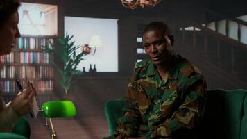 African american soldier in military uniform sits with an expert, viewing a Rorschach test illustration to share feelings and discuss trauma. PTSD and shell shock counseling session. Camera A. photo