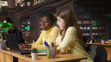 Primary school pupils in a library discuss during an online seminar, using tech to connect with educator and classmates for an interactive virtual chat. Remote lesson via web conference. Camera A. photo