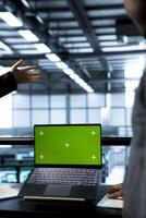 Employees in data center using green screen mockup laptop, analyzing metrics, optimizing storage volumes. Server hub workers using isolated screen chroma key notebook, ensuring seamless operations photo