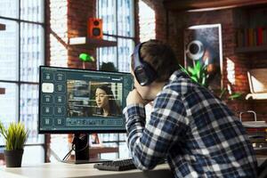 Man in home office listening music and using generative artificial intelligence GPT generating videos. Person wearing headphones uses AI virtual assistant producing clips from prompts photo