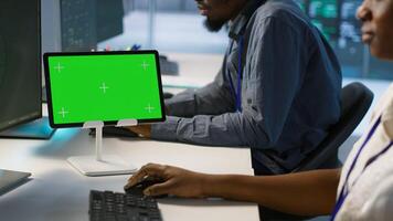 Close up of green tablet in server room used by system administrators to ensure minimal downtime. Data center software developers looking at chroma key device, monitoring performance, camera A photo
