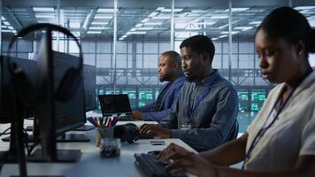 African american data center technicians implement AI predictive maintenance systems. Woman in server hub using artificial intelligence to identify hardware failures, camera A photo