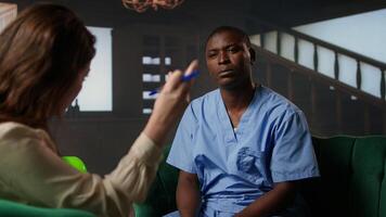 Black medical assistant being defocused and disconnected from reality, suffering from depersonalization and PTSD and receiving help from therapist. Male nurse opens up about struggles. Camera A. photo