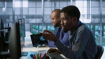 Cheerful coworkers in data center implementing AI predictive maintenance systems. Server room engineers using artificial intelligence to identify hardware failures impacting operations, camera A photo