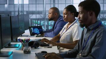 Technicians using computers and tablet in data center, implementing AI systems. Server farm experts using artificial intelligence on device to identify hardware failures impacting operations, camera A photo