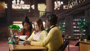 Preteens girls and their professor collaborating on schoolwork at the library, focused on academic materials to write a good essay. Students collect extra information with private lessons. Camera A. photo