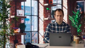 Employee completing spreadsheets on laptop and listening music. Worker in home office wearing headphones editing documents on notebook, updating reports and files, camera A photo