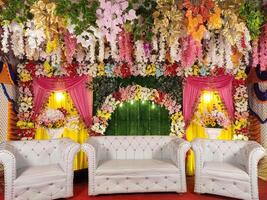 A stunning and festive floral decoration enhances the atmosphere, complemented by an elegant seating arrangement in vibrant colors, perfect for an indoor celebration event photo