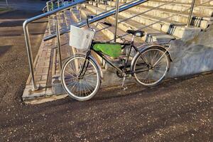 A bicycle with a basket stands near the porch with a railing. photo