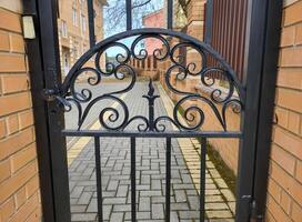 Beautiful wrought iron gate pattern with carvings between brick columns photo