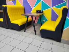 A table and bright yellow sofas in the cafe on the background of a multicolored wall. photo