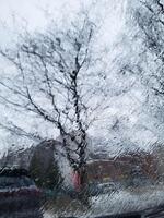 On a cloudy day, the windshield of the car is covered with rain streams. photo