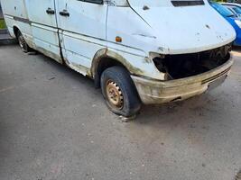 An old white rusty car with flat wheels. photo
