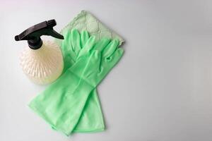 There are two light green rubber gloves, a napkin and a spray bottle on the table. A place for your text. photo