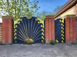 Wrought iron gates in the shape of a peacock with red brick columns. photo