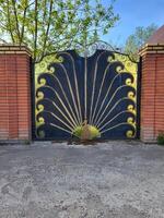 Wrought iron gates in the shape of a peacock with red brick columns photo