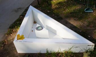 In the autumn garden there is a small triangular empty white pool with a lighting lamp. photo