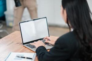 Professional woman using a laptop with a blank screen in an office setting, ideal for business and technology concepts. photo