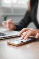 Close-up of a business professional using a smartphone and laptop, highlighting modern technology in a work environment. photo
