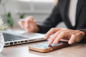 Close-up of a professional using a smartphone and laptop at a desk, highlighting modern work and communication. photo