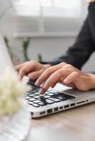 Hands typing on a laptop in a bright office, showcasing productivity and technology in a modern workspace. photo