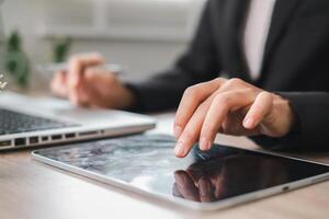 Close-up of hands using a tablet and laptop, symbolizing modern business technology and productivity. photo