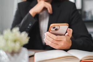 A business professional in a suit using a smartphone at a desk with an open notebook and a small plant, conveying a modern office environment. photo