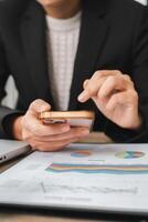 Close-up of a business professional using a smartphone to analyze financial data with charts and graphs in a modern office. photo