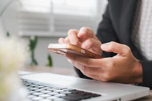 Close-up of a person using a smartphone and laptop, highlighting modern technology in a business environment. photo