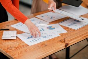 Business Team Analyzing Financial Data with Charts and Graphs on Wooden Desk in Modern Office Setting photo