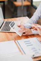 Close-up of hands using a calculator and laptop, analyzing financial charts and graphs in a professional office environment. photo