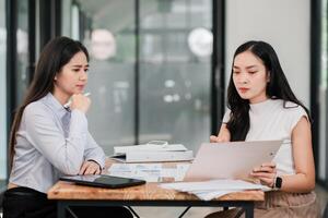 Professional Business Meeting Between Two Women Analyzing Documents in a Modern Office Setting with Technology and Charts photo