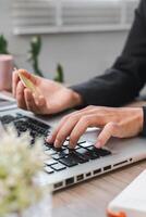 Close-up of Hands Using Laptop for Online Shopping with Credit Card in Modern Office Setting photo