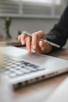 A hand using a laptop touchpad with a pen, symbolizing modern business and productivity in an office environment. photo