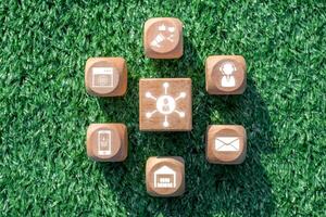 Wooden blocks with digital communication icons representing the omnichannel retail concept on a grass background. photo