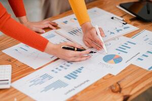 Close-up of hands working on financial documents with charts and graphs during a business meeting. photo
