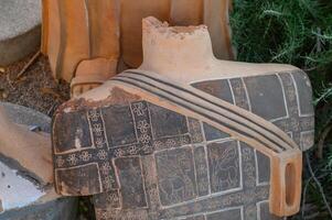Ancient pottery fragment with intricate carvings displayed in an archaeological site photo